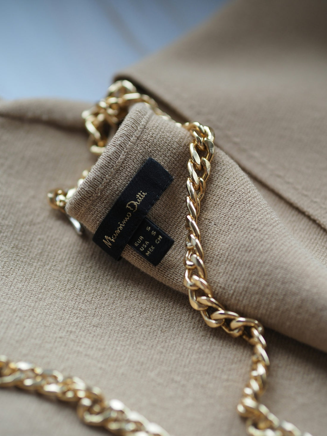 Chaîne dorée sur une veste sombre, détail